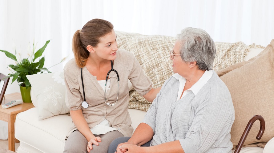 Pflegerin mit Stereoskop sitzt mit älteren Frau auf dem Sofa Pflegerin mit Stereoskop sitzt mit älteren Frau auf dem Sofa